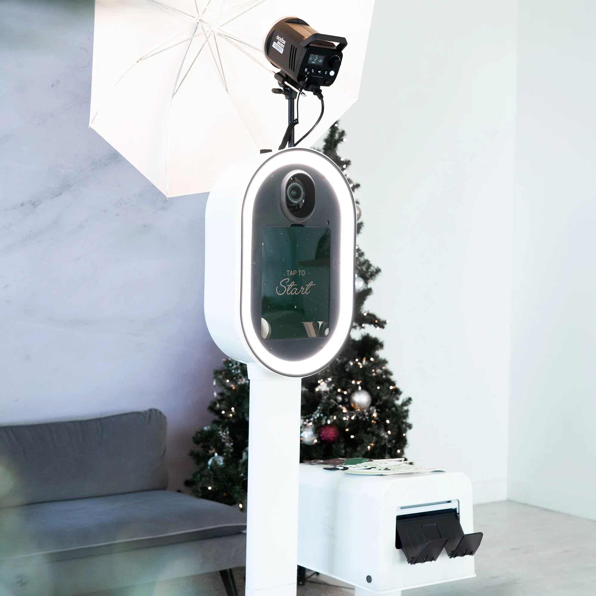 Guests at a cozy winter party pose with festive props in front of a glam photo booth setup featuring holiday décor and professional lighting.