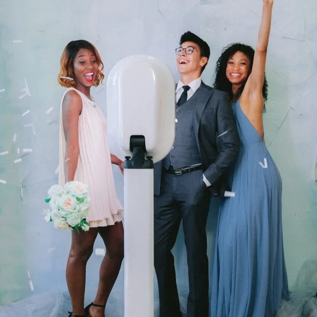 Guest enjoying a photo session in a modern open-air photo booth with glamorous lighting and custom props at a wedding reception.