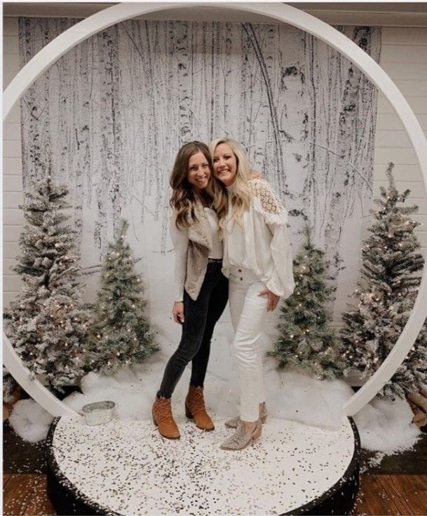 Guests posing in front of a winter-themed photo booth with snowflake props and a festive backdrop, smiling and bundled in cozy attire.