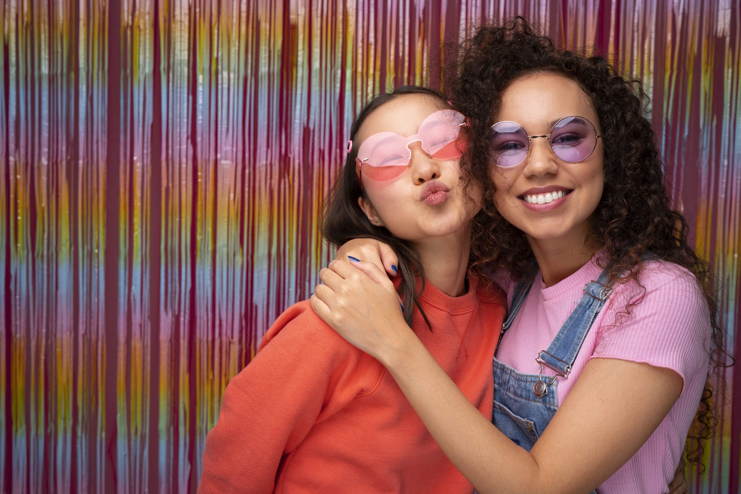 Guests laughing and posing in front of a glam photo booth with instant printouts at an outdoor birthday party.